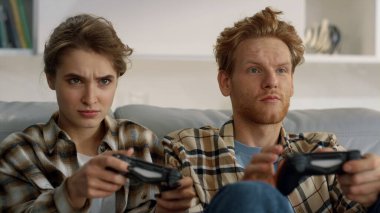 Oyuncular ellerinde joystickle evde eğleniyorlar. Oyuncular video oyunu seviyor. Gülümseyen kızıl adam evde online sanal savaşta zafer kazanıyor. Heyecanlı aile dinleniyor. Kontrolleri ellerinde tutuyor..