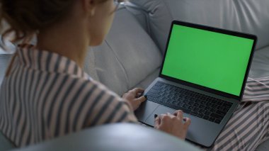 Uzaktan kumandalı iş yerinde yeşil ekran dizüstü bilgisayarı gibi görünen bir kadın. Hafta sonu kanepede pijamalı kız internette geziniyor. Tanımlanamayan gazeteci evde model bilgisayarda çalışıyor. Krom anahtar aygıtı kavramı.