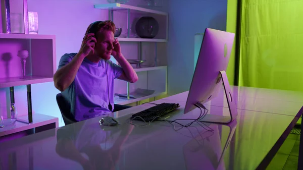 Gamer Putting Headphones Playing Computer Game Home Neon Lights Interior — Zdjęcie stockowe