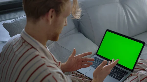 Guy using green laptop computer closeup. Online teacher talking video conference at home office. Unknown man manager finishing virtual meeting waving chroma key screen. Remote workplace at quarantine