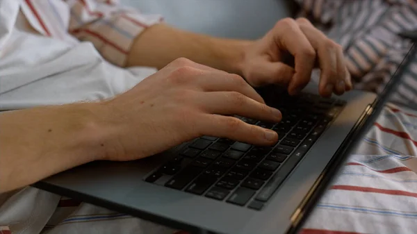 Freelancer hands typing laptop keyboard in pajamas closeup. Man working late preparing presentation project. Unknown businessman browsing web send email on weekend. Busy student studying use computer
