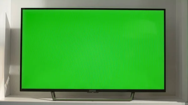 Chroma key smart TV in living room closeup. Device with blank screen in sunlight. Flat screen TV set mockup at home. Watching television shows streaming platforms movies. Weekend leisure time concept.