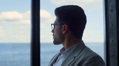 Başarılı yönetici ofis panorama penceresinde iş planlaması yapmayı düşünüyor. Uzaktan bakan dalgın iş adamı, gelecekteki kararları gözlüklü olarak değerlendiriyor. Erkek profesyonel konsept