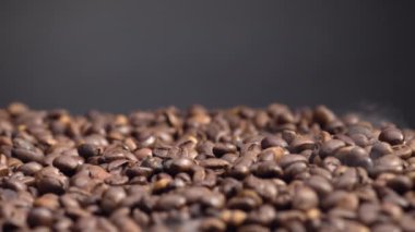 Yakın plan kavrulmuş kahve çekirdekleri. Kızartma makinesine dökülen mis kokulu tohumlar. Kahverengi fasulyeler ağır çekimde düşüyor. Mükemmel aromatik arabika öğütmeye hazırlanıyor. Sabah içkisi..