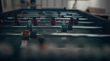 Futbol masasındaki minyatür plastik figürleri kapatın. Tanınmayan çocuklar çubukları döndürür oyuncuları gol atmak için döndürür. Okul arkadaşları lobide mini futbol oynuyorlar.