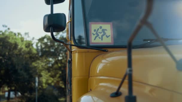 駐車場の空のスクールバススタンドを閉じます 警告標識画像を持つ黄色の学術車両が子供を実行している クラスの後に家庭を駆動するためにアメリカの輸送 フロントガラスミラービュー — ストック動画