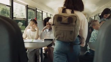 Okul servisinde sabah vakti çok kültürlü öğrenciler oturuyor. Çeşitli çocuklar akademik mekikte mutlulukla içme suyu konuşuyor. Okul çocukları geziye gitmek için okul otobüsüne bindiler. Eğitim kavramı.