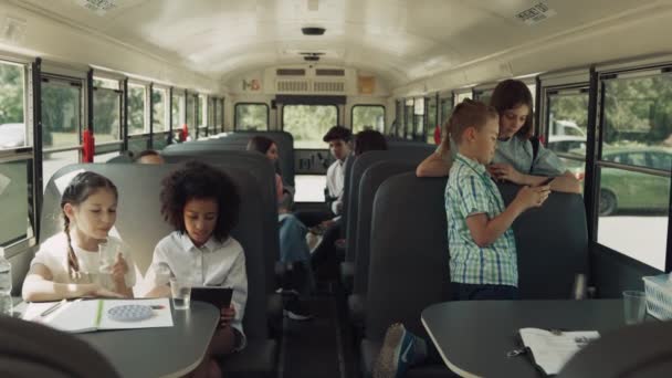 Diversos Compañeros Clase Adolescentes Sentados Juntos Autobús Escolar Hablando Clase — Vídeo de stock