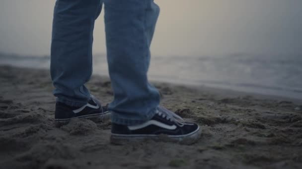 Close Man Benen Stijlvolle Sneakers Staan Zandstrand Zee Onherkenbare Mannenvoeten — Stockvideo