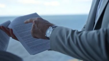 Ortaklar deniz manzarasında sözleşme detaylarını tartışıyor. Kapanış el işareti kağıtları. Tanınmayan işadamı yöneticisi mali hukuki raporları astlarıyla kontrol ediyor. Tatminsiz müşteri kavramı.