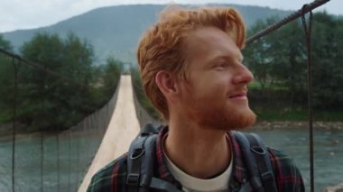 Yakın çekim mutlu hipster yaz manzarasında dağlarda yürüyüş. Pozitif sırt çantalı biri nehir köprüsünde yeşil doğayı keşfediyor. Gülümseyen turistler doğa yürüyüşünden hoşlanırlar. Seyahat yürüyüşü kavramı.