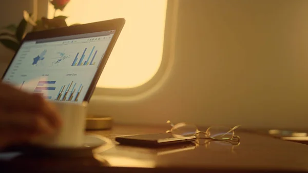 Hands working laptop charts on private jet closeup. Company ceo analyzing data statistics on corporate trip. Unknown businesswoman check sales stock diagram in luxury aircraft. Business travel concept