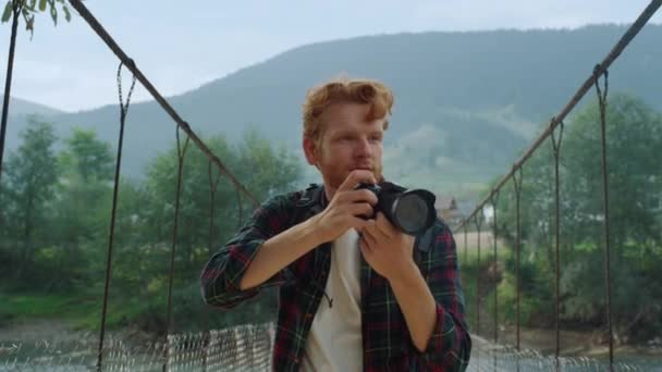 笑顔の写真家を閉じる屋外で山の風景をお楽しみください 自然の中でデジタルカメラを使って楽しい観光客が写真を撮る ヒップスター千年紀川の橋の上に画像を探している 旅行ブログのコンセプト — ストック動画