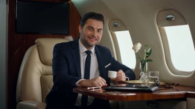 Gülümseyen CEO uçak penceresinde tek başına poz veriyor. Başarılı bir adam, şirket seyahatinin tadını çıkarır. Kendine güvenen şık bir işadamı birinci sınıf lüks içinde uçuyor. Zarif beyefendi yolculukta dinleniyor.
