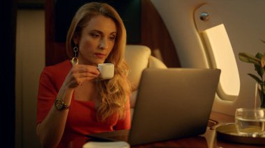 Lüks CEO şirket gezisinde dizüstü bilgisayarda çalışıyor. Odaklanmış sarışın kahve içiyor ve birinci sınıf uçuşta dinleniyor. Çekici, güzel iş kadını internet kontrol maillerini karıştırıyor. Özel jet konsepti