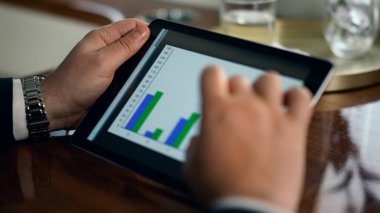 Tablet kullanan bir finans uzmanı. Kapanış adamı elleri ekrandaki grafiklere dokunuyor. Tanınmayan işadamı şirket haritalarını analiz ediyor. İş analisti denetleme şirketinin şeması üzerinde çalışıyor.