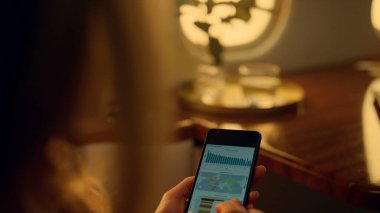 Akıllı telefon çizelgelerini tutan eller yakın plan. Bilinmeyen CEO iş seyahati üzerinde çalışıyor. Tanınmayan iş kadını bir finans analisti lüks bir uçakta cep telefonu kullanıyor. Seyahatte kurumsal verileri kontrol et