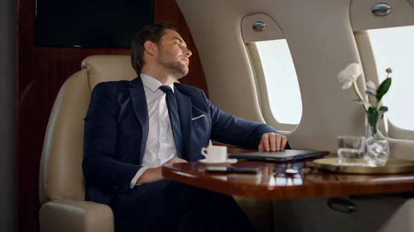 European businessman finishing work closing laptop. Tired man lean airplane seat looking window. Thinking stressed man analyst resting on corporate trip after hard day. Business lifestyle concept.