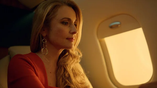 Successful ceo talking virtual meeting closeup. Wealthy blonde dreaming on jet. Confident beautiful businesswoman finishing video call looking window in golden sunlight. Business traveling concept