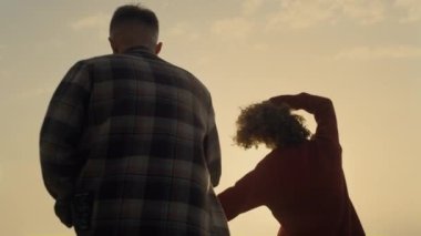 Sahilde el ele tutuşan sevgi dolu bir çift. Neşeli kadın ve erkek gün batımında deniz kıyısında yürüyorlar. Oyuncu kız ve erkek romantik vakit geçiriyorlar. Genç hippiler eğleniyor. Aşk konsepti 