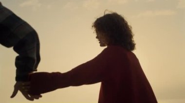 Romantic couple dating on beach at sunrise. Loving woman and man holding hands. Happy lovers having fun on beach at sunset. Fashionable girl and guy spending summer vacation at sea. Happiness concept 