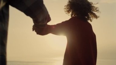 Happy woman and man walking on beach at sunset. Closeup lovely couple holding hands. Stylish girl and guy hugging each other at ocean shore. Young family enjoying honeymoon together. Romantic concept