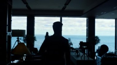 Karanlık siluet meslektaşları panoramik pencere işyeriyle buluşuyor. Lüks okyanus manzaralı ofiste yönetici kadın patron. Tanımlanamayan iş adamları birlikte çalışıyor. Şirket yaşam tarzı kavramı