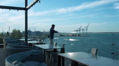 Confident man resting outdoors dreaming at sea view. Cafe owner enjoying morning on luxury terrace. Focused businessman manager relaxing on hotel rooftop. Thinking guy dreaming of life success alone