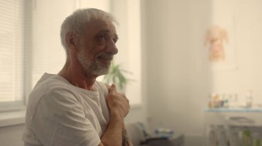 Hastane ofisinde aşı yaptıktan sonra omuz omuza duran minnettar yaşlı bir adam. Çok ırklı kadın doktor aşısı sağlık kliniğinde kıdemli hasta. Dokunulmazlık Emeklileri kavramı.