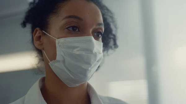 African woman professional medic listening patient health complaints in mask close up. Portrait of doctor working hospital in covid pandemic period. Young physician conduct consultation on vaccination