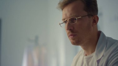 Hastanede çalışan odaklanmış doktor bilgisayarı kapat. Portre genç ciddi doktor modern klinik dolabında monitör izliyor. Dijital teknoloji salgın hastaları tedavi etmeye yardımcı oluyor..