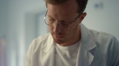 Tıp dergisine notlar yazan erkek cerrah hastane ofisini kapatıyor. Modern klinikte çalışan yakışıklı bir doktor. Hekim kabinede tıbbi evrak işleriyle uğraşıyor..