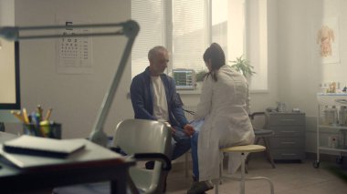 Profesyonel doktor, yaşlı hastanın koluna kelepçe takıyor. Yaşlı adam modern hastanedeki terapisti ziyaret ediyor. Klinikte emeklilerin sağlığını inceleyen kadın doktor. Sağlık hizmetleri kavramı.