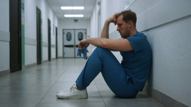 Stresli cerrah zor bir ameliyattan sonra boş klinik koridorunda kalıyor. Depresyonda olan doktor hastane koridorunda tek başına oturuyor. Mutsuz doktor, tıbbi eldiven fırlatıyor. El ele tutuşuyorlar..