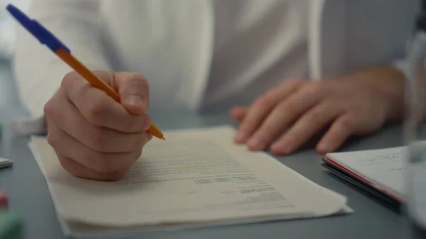 Doctor hands writing medical documents close up. Unknown medicine worker filling journal fixing patient health history on hospital desktop. Physician working noting treatment appointment in clinic.