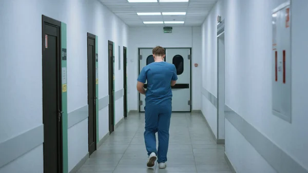 診療所の廊下で会話した後 患者を助ける急いで2人の医師 看護師立ち廊下でレポートを議論した後 深刻な男医師が離れて歩きます 病院のホールで二つの医学の多様性 — ストック写真