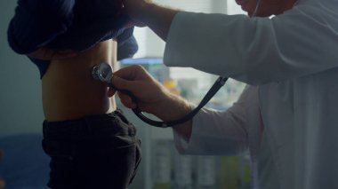 Doktor elleri steteskop kullanarak akciğer hastası kızı dinliyor. Afrika kökenli Amerikalı genç çocuk klinikte genel sağlık muayenesinden geçiyor. Çocuk doktoruna geri çekilen bilinmeyen bir çocuk..