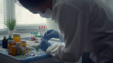 Ciddi bir hasta aşı olmayı bekliyor. Koltuk modern kliniği kapatıyor. Doktor kapalı alandaki insanlar için covid aşısı hazırlıyor. Profesyonel doktor elleri ilaç şişesine iğne sokuyor..