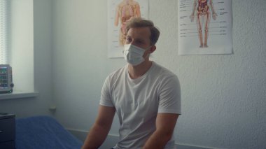 Caucasian man patient listening doctor appointment sitting in modern hospital close up. Serious guy consulting with physician about covid vaccination. Medical worker noting data on digital tablet.