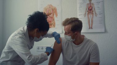 Doktor enjeksiyonu insan omzuna yapıyor. Deri altı iğnesini yakından kullanıyor. Afrikalı kadın doktor modern klinikte aşı yapıyor. Hastanedeki tıbbi aşı uzmanı..