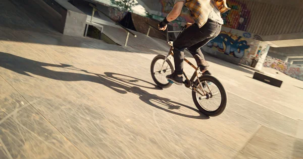 Young biker performing rail stunt at urban skate park. Closeup active rider racing on bmx bike on ramp outdoors. Closeup extreme man doing dangerous jump with bicycle at skatepark. Sport concept.