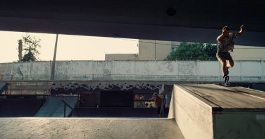 Gençler kaykay paten üzerinde atlama numarası yapıyor. Şehir merkezinde bisiklet sürüyor. Ekstrem insanlar kaykay parkında vakit geçiriyorlar. Ekstrem spor sağlıklı aktif yaşam tarzı gençlik kültürü kavramı. 