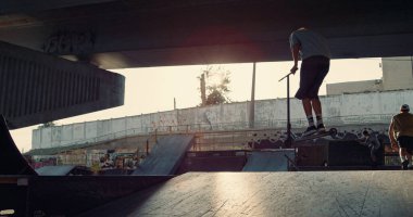 Sportif gençler kaykay ve BMX bisikletiyle şehir kaykay parkında antrenman yapıyorlar. Arkadaşlar dışarıda ata biniyor, eğleniyor. Aktif eğlence eğlence yaşam tarzı alt kültür kavramı. 