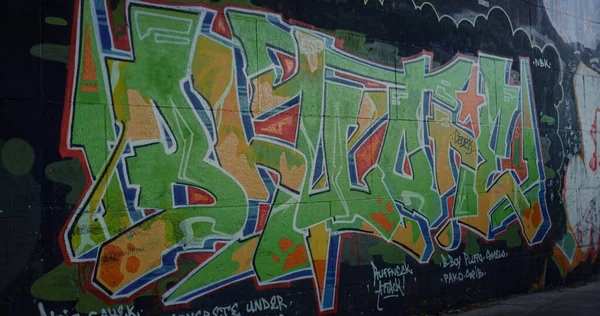 スケートパークの壁にカラフルな落書き スケートパークでエアロゾルカラースプレーでストリートアートの図面を閉じます 壁に異なる色のパターン 都市のサブカルチャー自己表現現代美術の概念 — ストック写真