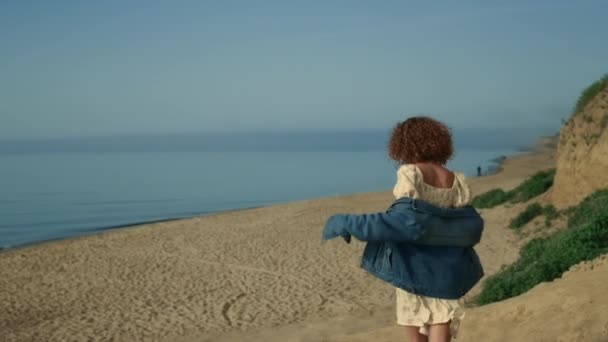 소녀가 아침에 해변으로 뛰어내려 옵니다 아름다운 해변을 곱슬머리 행복하다 매력적 — 비디오