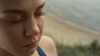 Kapanış kızı yaz sabahı sahilde meditasyon yapıyor. Yoga yapan odaklanmış bir kadının portresi açık havada gözlerini kapalı tutuyor. Genç sporcu bayan dışarıda deniz kenarında Pranayama eğitimi alıyor. Spor konsepti