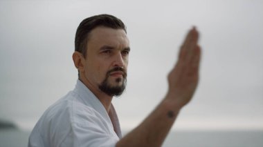 Kumsal kasvetli bir günde spor yapan atletik bir adam yaklaşıyor. Açık havada beyaz kimono giyip karate antrenmanına odaklanmış. Dövüş sanatları yapan güçlü bir sporcu. Yumruk atıyor.. 