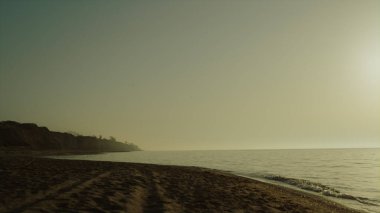 Yaz mevsiminin şafağında kumlu güzel bir sahil. Sakin okyanusun yanında doğa manzaralı bir sabah. Boş deniz kıyısının altında açık bir gökyüzü. Gün batımında geniş deniz kıyılarını yıkayan deniz dalgalarının manzarası..