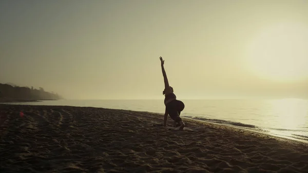 ビーチで美しい朝の日の出を楽しむヨガの女性 板を作るスポーティ若い女の子は屋外で手を上げるポーズ 夏に砂の海岸にストレッチスリムスポーツ女性 スポーツライフコンセプト — ストック写真
