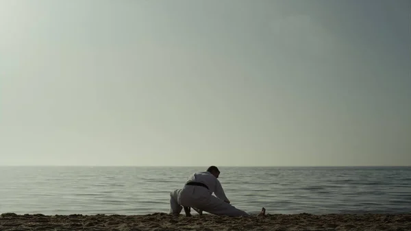 Karate Άνθρωπος Κατάληψη Τεντώνει Πόδια Στην Αμμώδη Παραλία Ενεργός Αθλητής — Φωτογραφία Αρχείου
